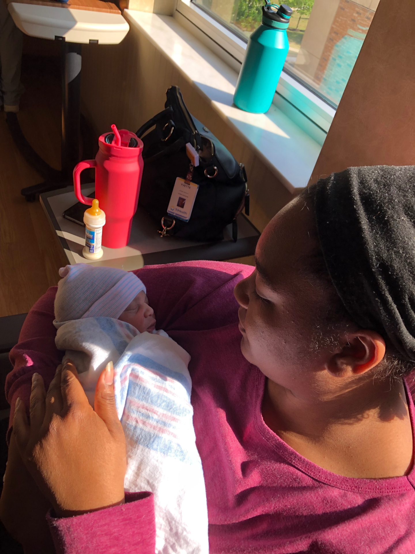 Mother holding her newborn in the sunlight